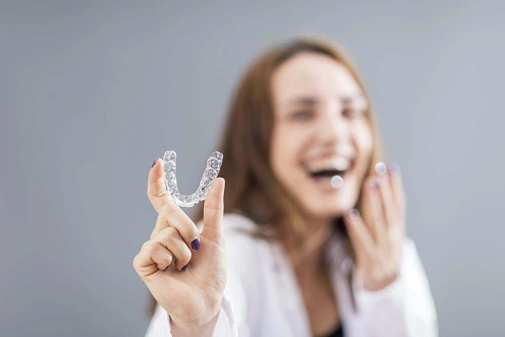 smiling-woman-holding-invisalign-bracer